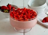 Coppa con mousse di fragole e coppette e fragole sullo sfondo