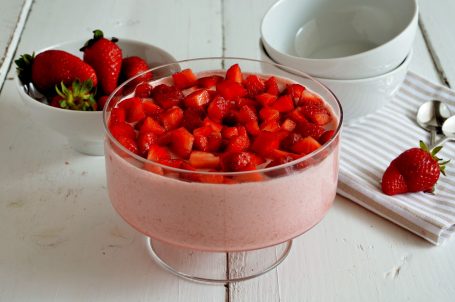Coppa con mousse di fragole e coppette e fragole sullo sfondo
