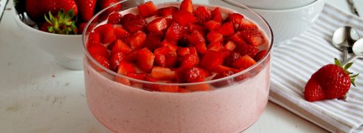 Coppa con mousse di fragole e coppette e fragole sullo sfondo