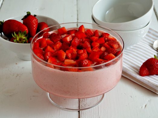 Coppa con mousse di fragole e coppette e fragole sullo sfondo