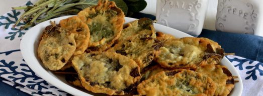 Piatto bianco con salvia fritta su tovaglia blu e bianca con salvia sullo sfondo