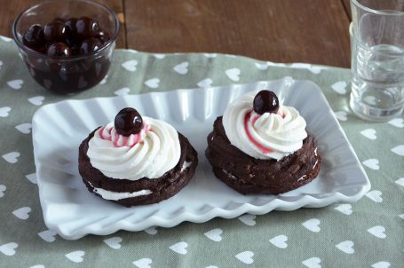 Zeppole al forno al cacao farcite con ricotta e amarene sciroppate su piatto da portata