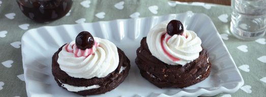 Zeppole al forno al cacao farcite con ricotta e amarene sciroppate su piatto da portata