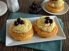 Zeppole di San Giuseppe al forno con crema pasticcera e amarene su piatto bianco