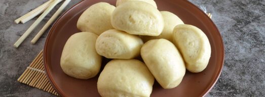 Piatto fondo con 9 mantou su tovalietta di bambù con bacchette