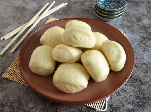 Piatto fondo con 9 mantou su tovalietta di bambù con bacchette