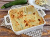 Teglia da forno bianca con parmigiana di zucchine calda e filante