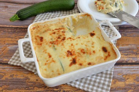 Teglia da forno bianca con parmigiana di zucchine calda e filante