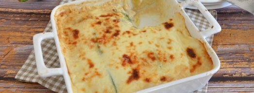 Teglia da forno bianca con parmigiana di zucchine calda e filante