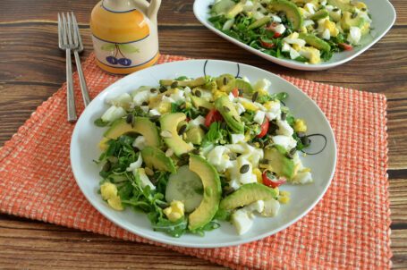 Piatto piano con insalata con uova sode e avocado su tovaglietta arancione
