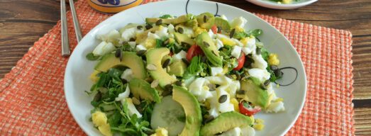 Piatto piano con insalata con uova sode e avocado su tovaglietta arancione